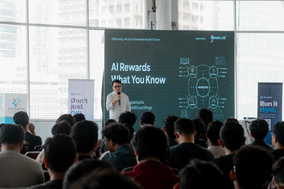 Anas berbicara di depan peserta dengan slide AI Rewards What You Know di layar